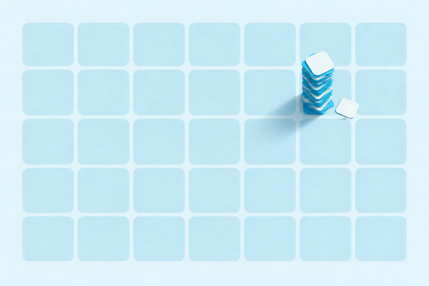 A grid of soft rounded squares laid out like a calendar month, with one square holding a tall stack of small cards casting a long shadow and a single card that has slipped onto the next square, while every other square sits empty